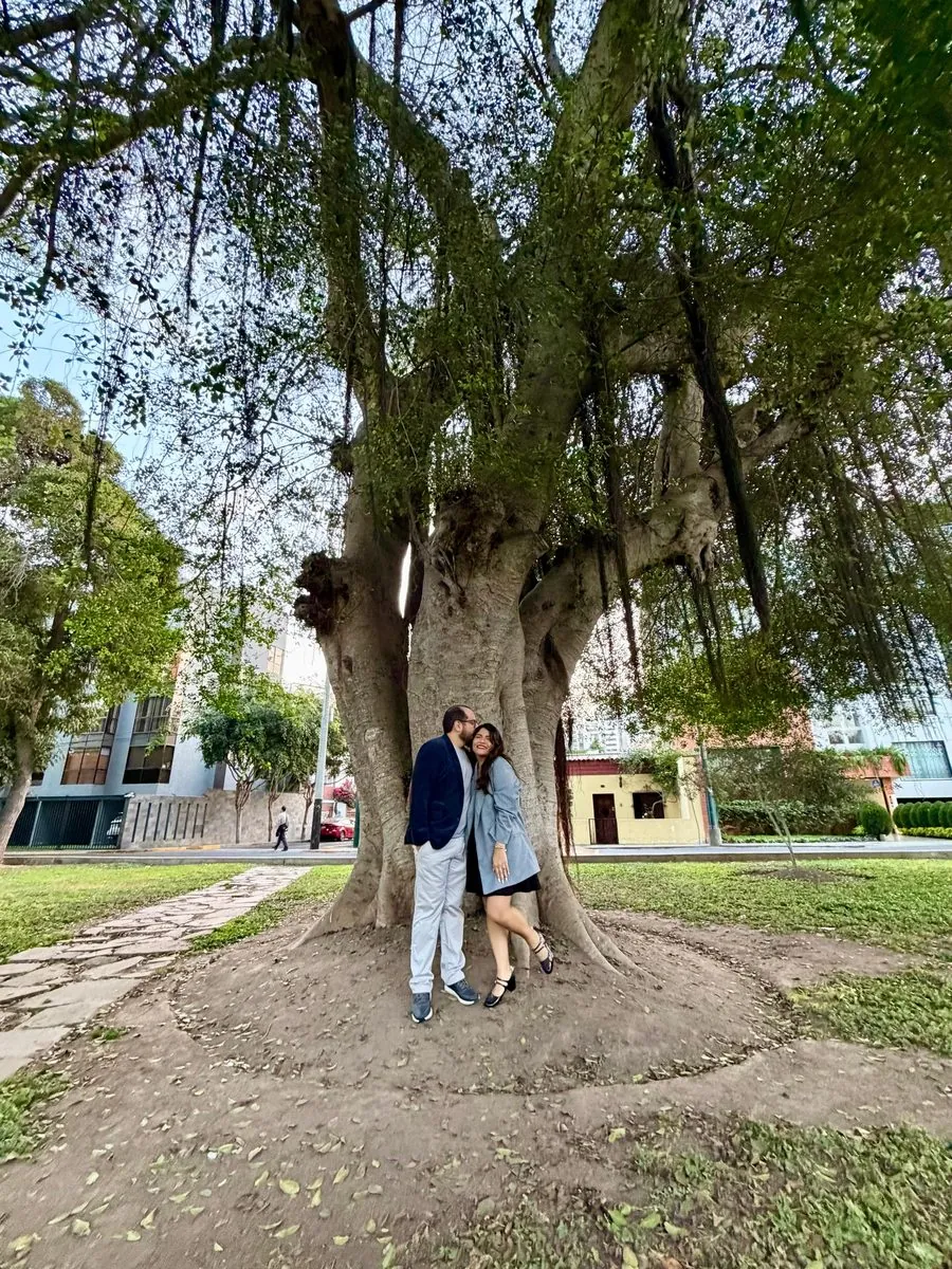 Lourdes y Yoel sonriendo bajo un gran árbol
